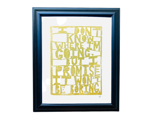 Framed  linoleum block relief print with gold text quoting David Bowie: "I don't know where I'm going but I promise it won't be boring" on a white background