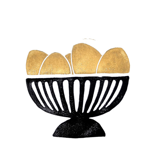 Decorative bowl with gold and black eggs in bowl on a white background