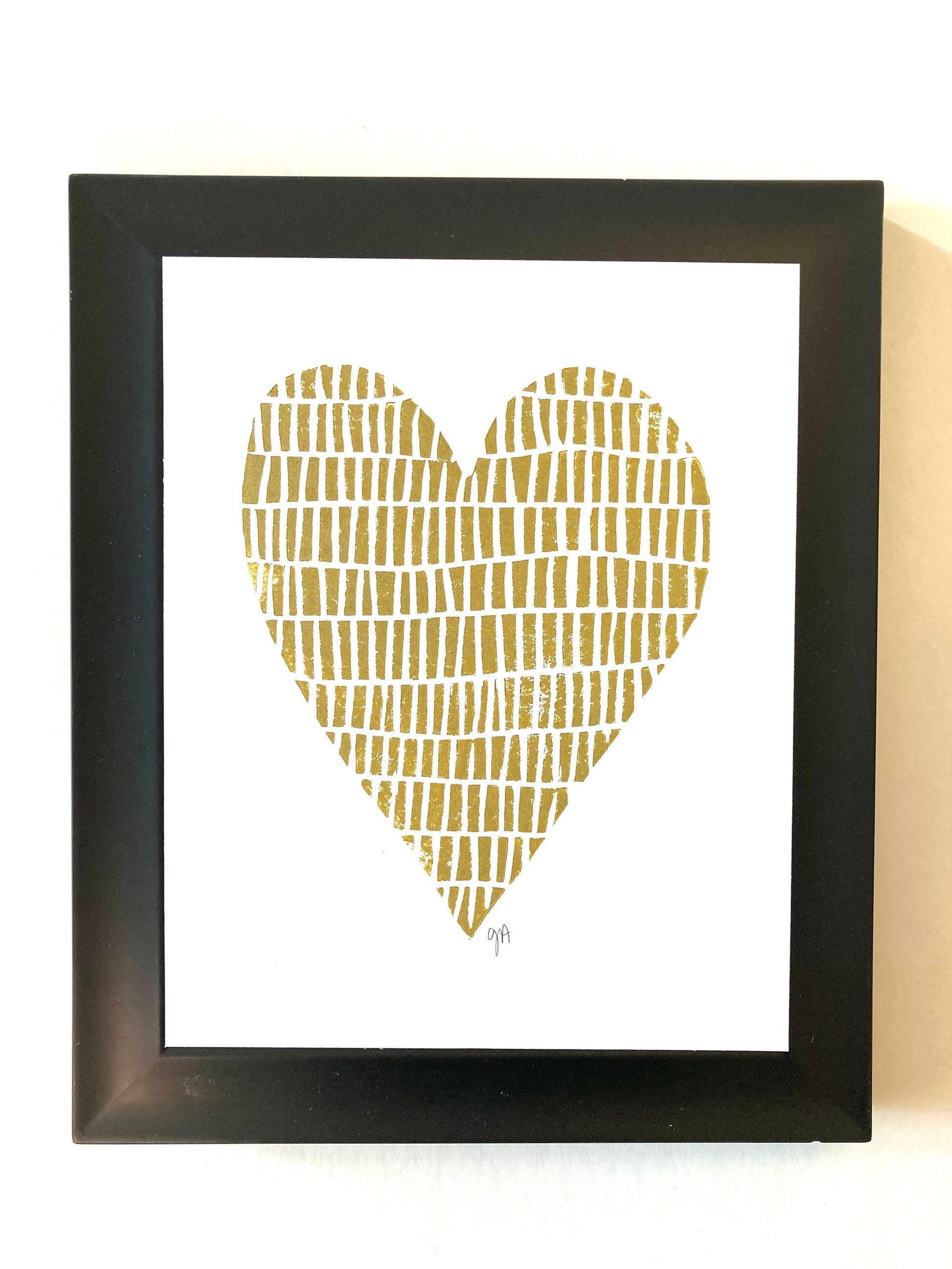 Framed artwork with a gold heart design on a white background