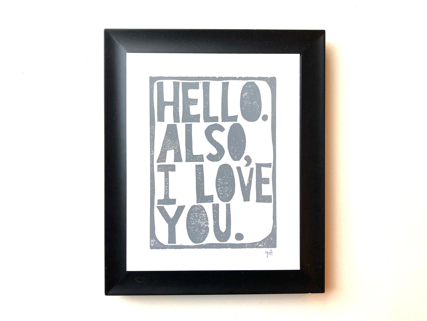 Framed print with 'Hello. Also, I love you.' text on a white background