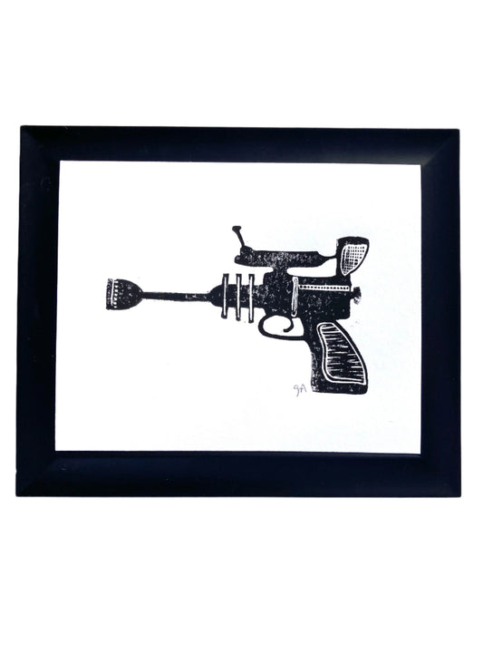 Framed black and white illustration of a ray gun on a white background