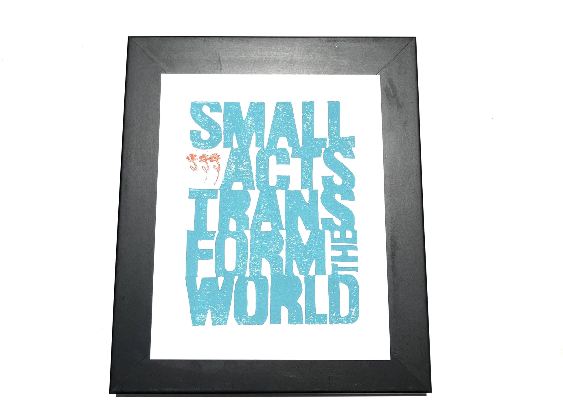 Framed print with motivational quote 'Small acts transform the world' in blue text on a white background