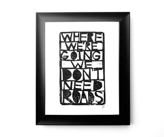 Framed black and white text art print with a quote on a white background Where we're going we don't need roads